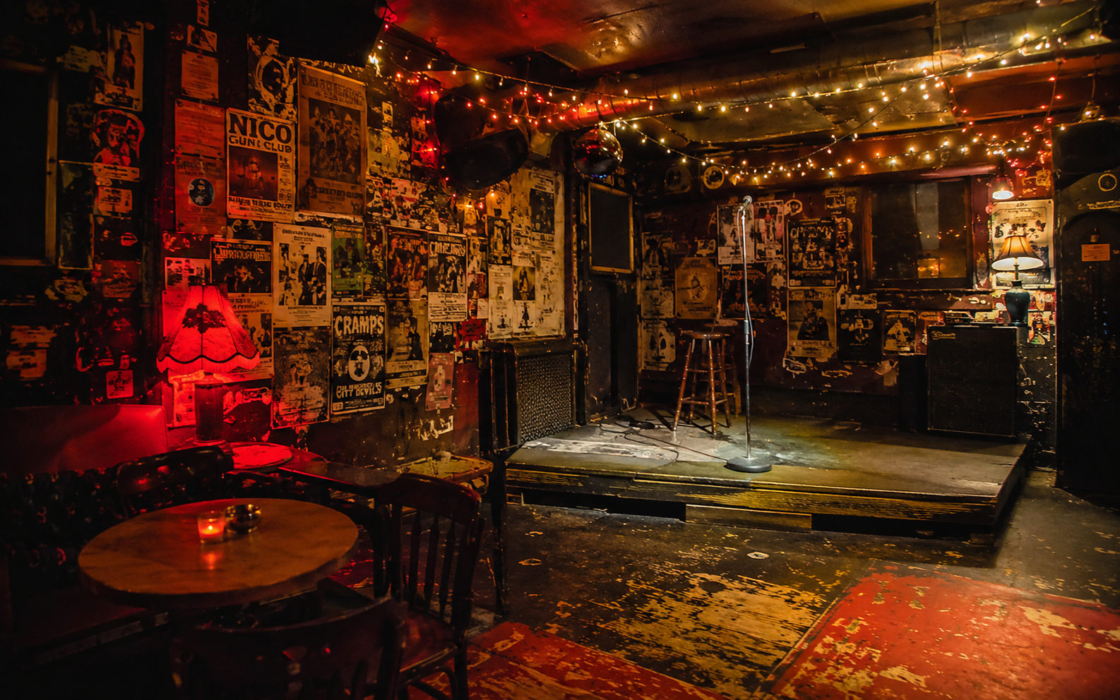 A cramped dive bar with instruments on a tiny stage